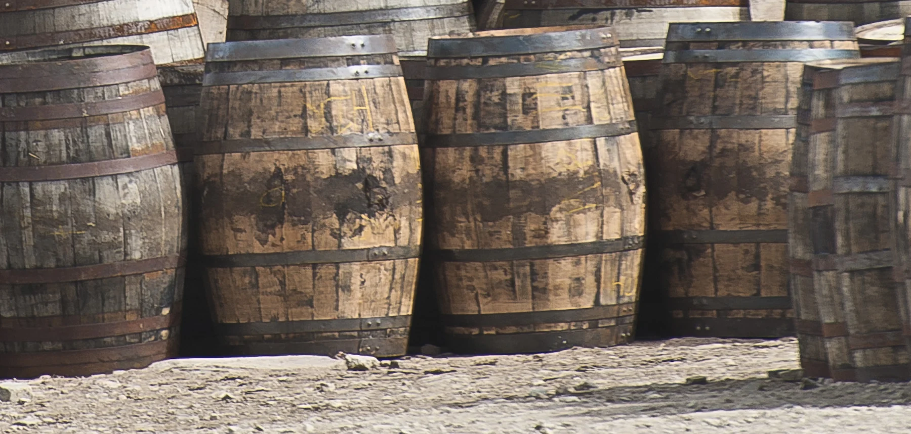 Weathered oak staves and metal hoops on upright casks at Speyside Cooperage, Aberlour