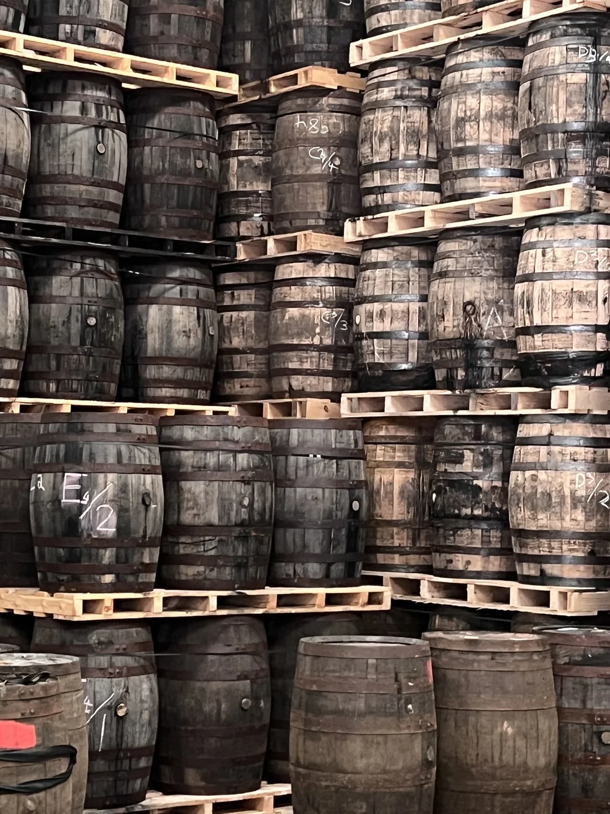 Wooden casks stacked on pallets in a warehouse